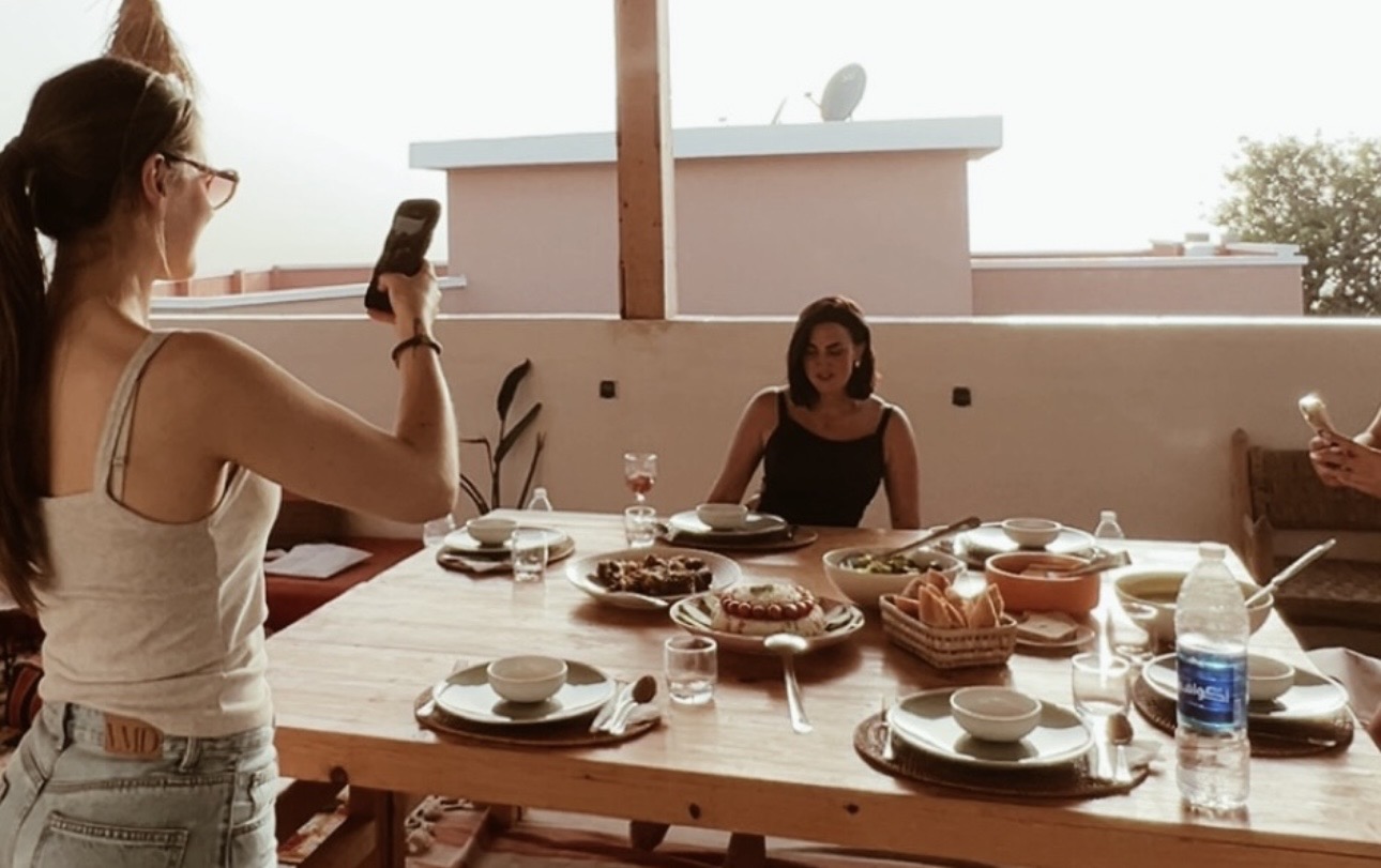 Women sharing a meal around a sunlit wooden table